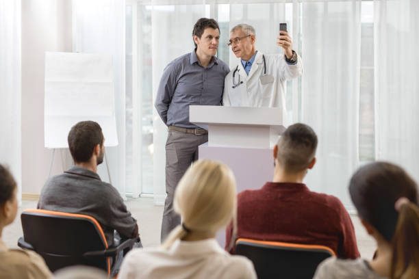 istock Smiling doctor and businessman taking a selfie on education event. 496852112