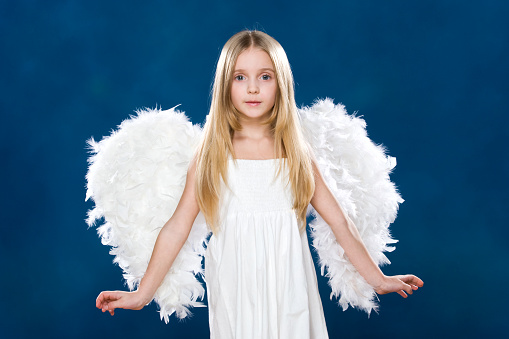 Portrait of happy angel wearing white clothing and wings over blue background     Note to inspector: the image is pre-Sept 1 2009