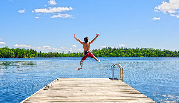 istock Young man running off dock on beautiful summer's day 496853283