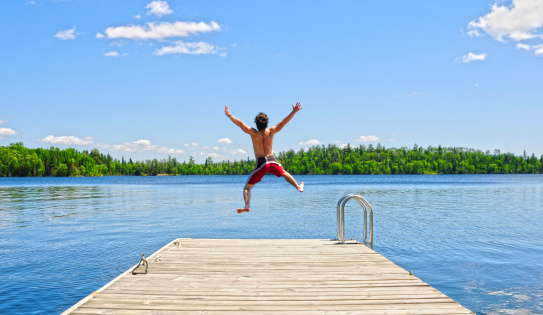 Young man running off dock on beautiful summer's day