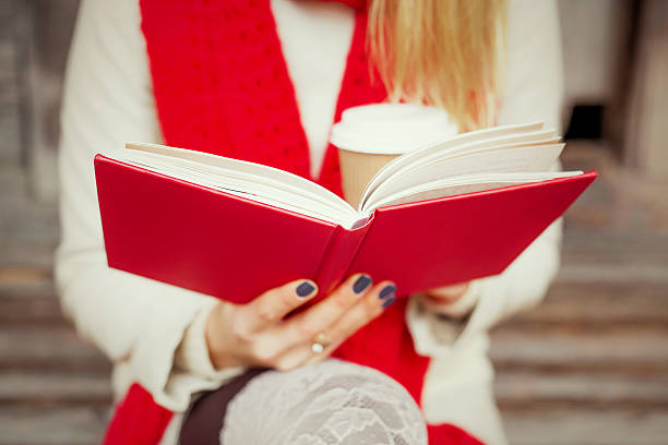 istock Woman reading outside and holding a coffee cup 496853838