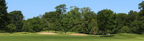istock Wide panorama image of golf course, bunkers, trees, blue sky 496855617