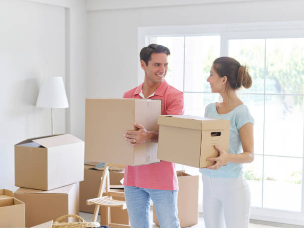 istock Couple Carrying Cardboard Boxes And Smiling 496858954