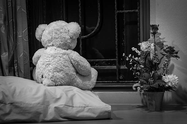 istock Teddy bears looking through the window sitting on window-sill - 496860308
