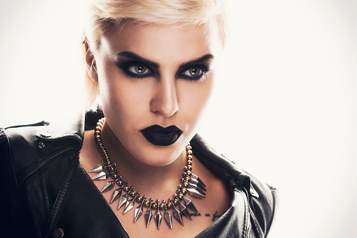 Portrait of a beautiful blonde woman with a black smokey eyes make-up and black lips, wearing black ramones leather jacket.