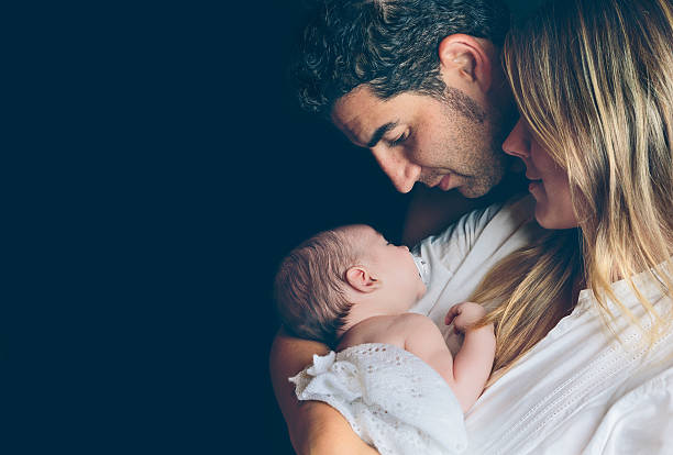 istock Happy couple embracing and looking newborn over dark background 496861922