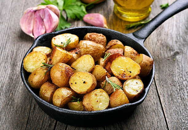 Roasted potato in frying pan Roasted potato in frying pan on wooden background salt seasoning stock pictures, royalty-free photos & images