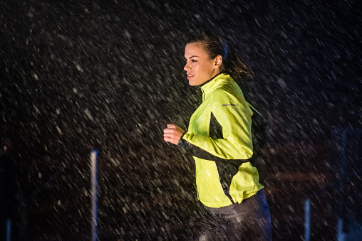 Mid adult woman wearing sportswear and jogging in rain.