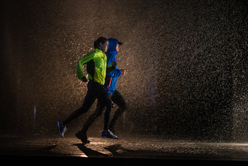 Man and woman wearing sportswear and jogging on pavement in city.