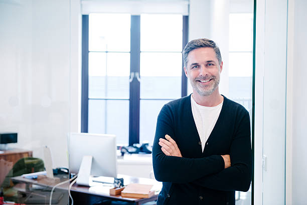 istock Attractive casual businessman in modern office, arms folded 496880114