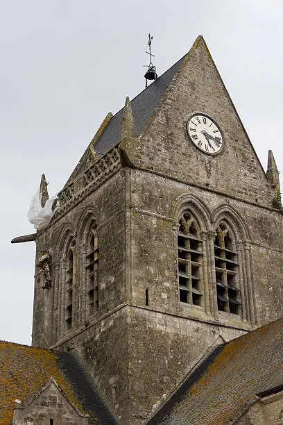 Dummy of the unlucky paratrooper hanging on the tower of the church of St. Mére Eglise.