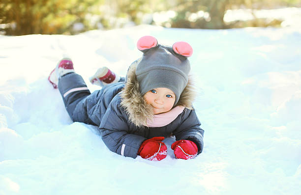 istock Happy little child lying playing on snow in winter day 496881154