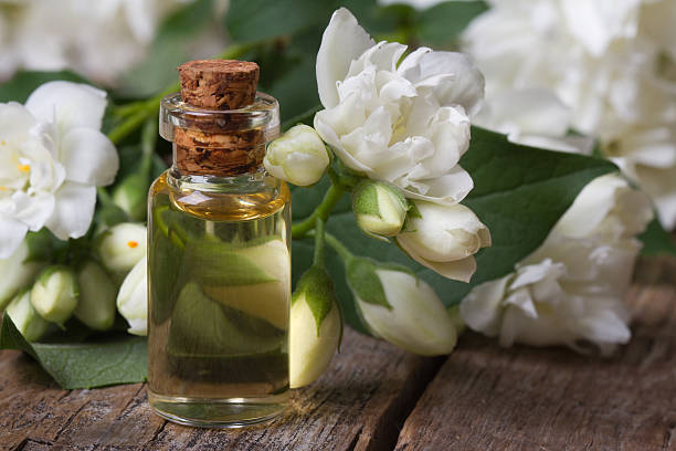 bottle of fragrant jasmine essence closeup and flowers bottle of fragrant jasmine essence closeup on the table and flowers. horizontal. jasmine photos stock pictures, royalty-free photos & images