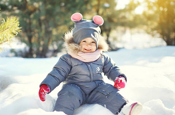 szczęśliwy uśmiech małe dziecko grając na śniegu w zimie dzień - winter child coat baby girls zdjęcia i obrazy z banku zdjęć