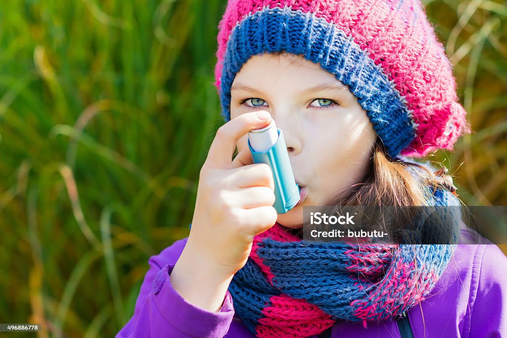 Niña utilizando inhalador de asma en un día de otoño - Foto de stock de 2015 libre de derechos