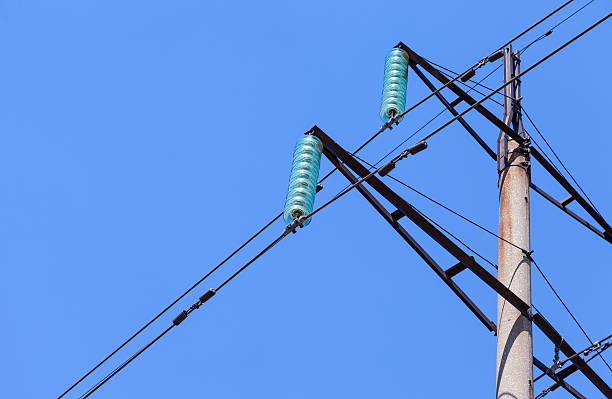 alta tensión eléctrica de torre contra el cielo azul - nonconductor fotografías e imágenes de stock