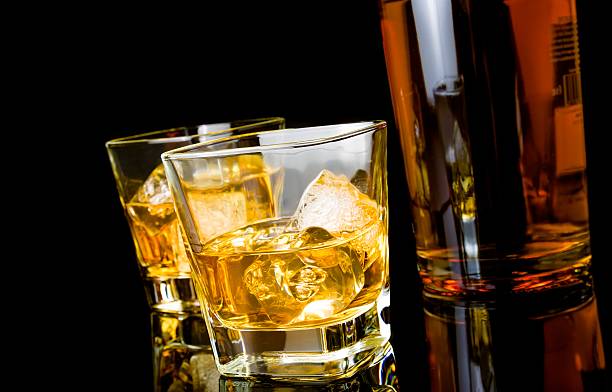 istock whiskey with ice in glasses near bottle on black background 496917468