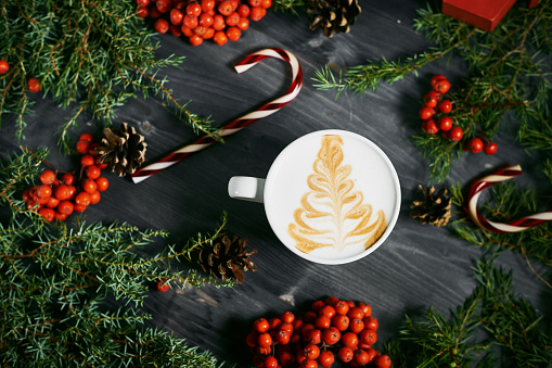 Cup of coffee with a Christmas tree pattern on a wooden Christmas background 