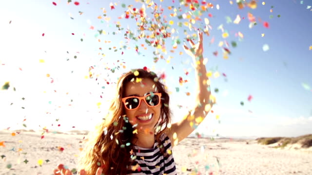 Woman throwing confetti in slow motion on the beach