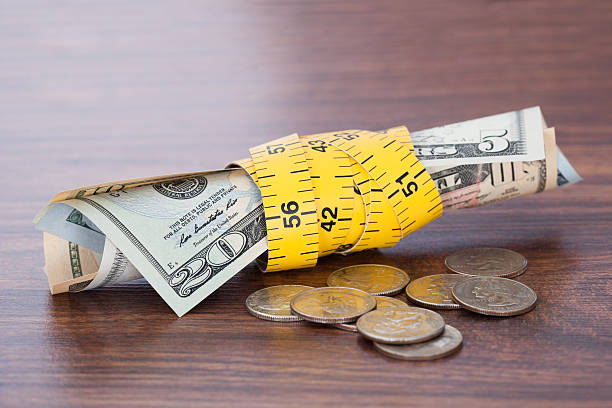 istock Banknotes Wrapped With Measure Tape By Coins On Table 496921136