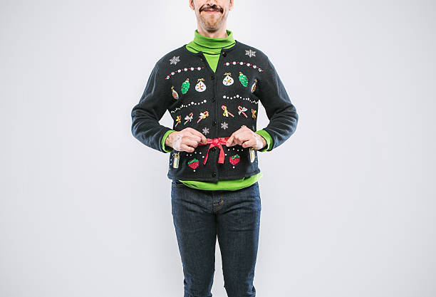 Christmas Sweater Man A young man with a mustache in a Christmas sweater covered in decorations and ugly kitsch ornaments smiles proudly, showing of his clothing.  Cropped at top of face, emphasis on the sweater.  White studio background with copy space. nerd sweater stock pictures, royalty-free photos & images