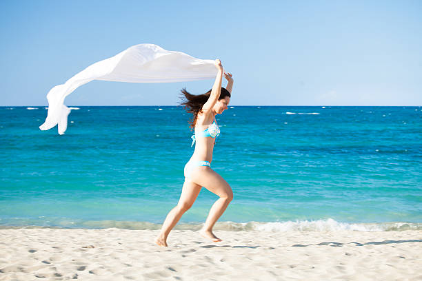 istock Woman With Sarong Running On Beach 496922226