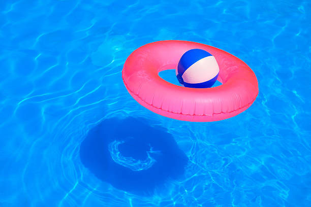 coloré de ballon gonflable et round tube flottant sur la piscine - beach ball swimming pool ball child photos et images de collection