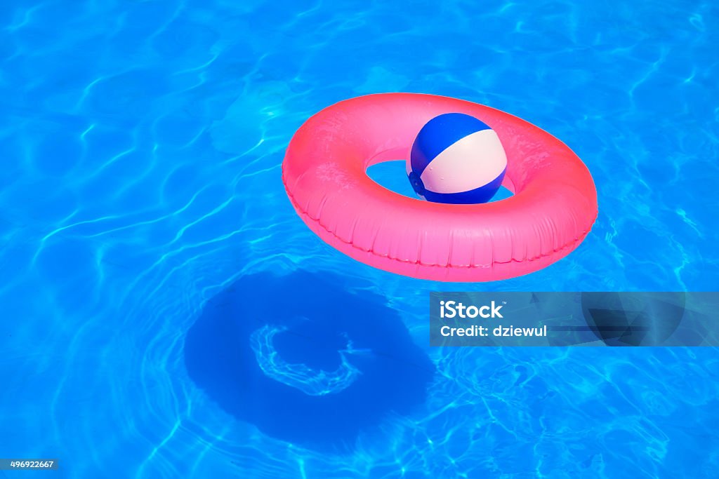 Colorful inflatable ball and round tube floating in swimming poo Colorful inflatable ball and round tube floating in swimming pool Swimming Pool Stock Photo