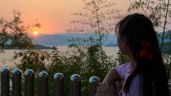 Happy young woman standing watching the sunset over the lake