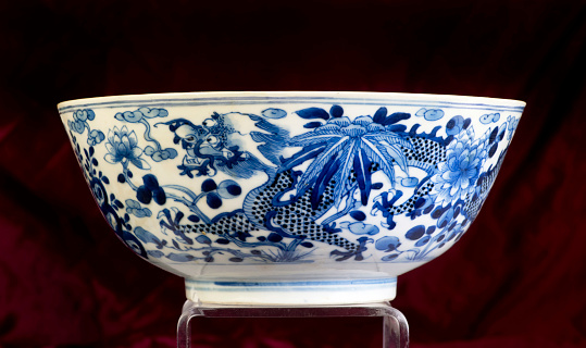 Horizontal extreme closeup photo of the blue leaves and rose flower pattern decorating a French antique ceramic covered soup tureen in a dining room. Provence, south of France.