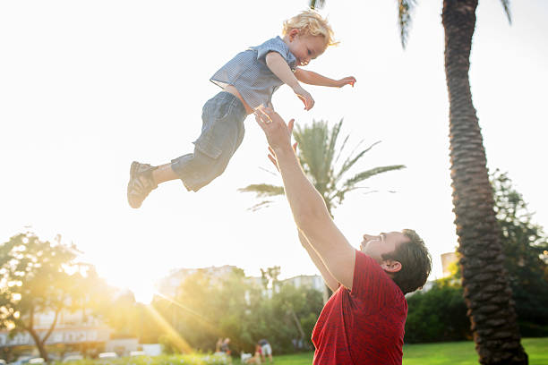 istock Playful father throwing his little boy high up. 496947104
