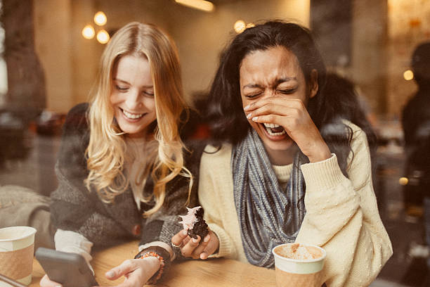 Laughing out loud Girlfriends using Smartphone in Coffeeshop dumbo new york photos stock pictures, royalty-free photos & images