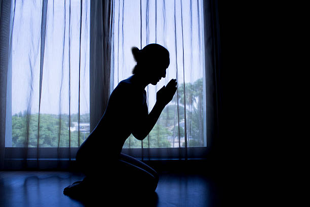 istock Woman Sitting Down In Prayer Silhouette 496954612