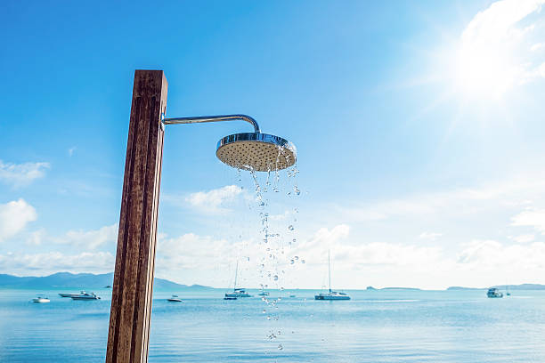shower head with water droplets on seashore and blue sky background