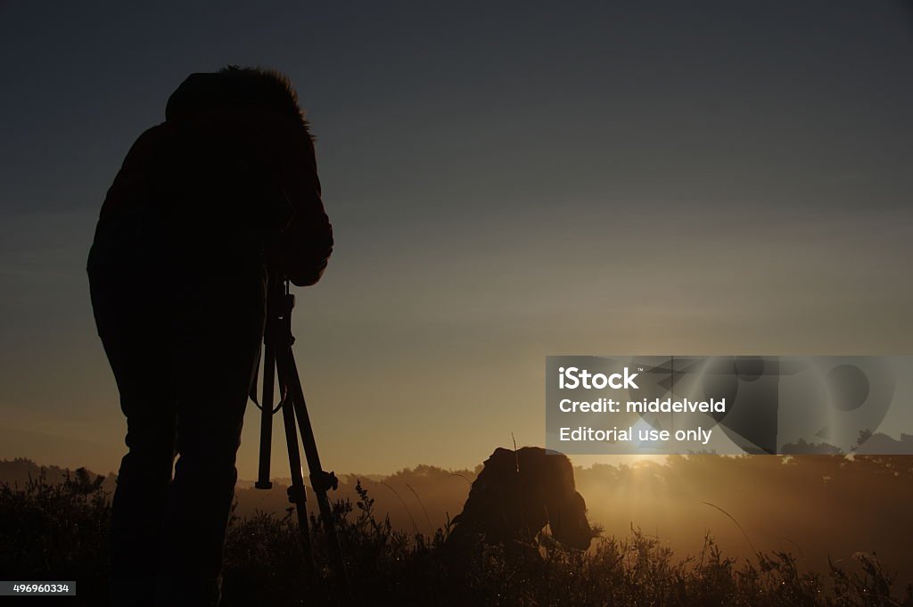 Photographing the sunrise Brunssummerheide, the Netherlands - November 1, 2015: Photographing the sunrise in the heathland. The beginning of a new day. 2015 Stock Photo