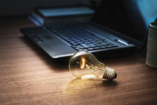 istock light bulb on wooden table with laptop 496960946