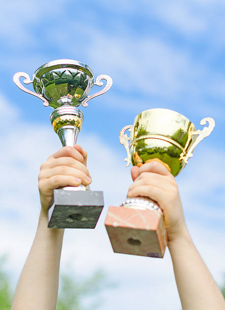 istock Hand of winner with gold and silver cups. 496973743