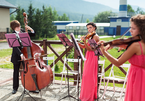 Quartet of classical musicians playing at a wedding outdoors near the river