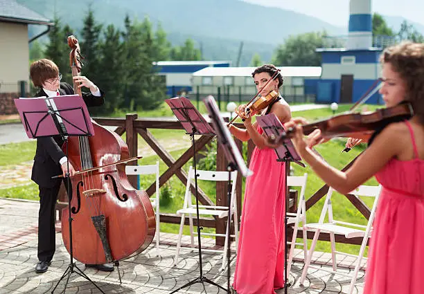 Photo of Girl violinist and bassist guy play outdoors