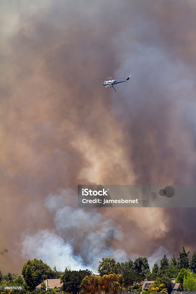 Helicopter Flying by Fire In Southern California Helicopter surveys area over fire burning near large homes in Southern California.  Poinsettia Fire - Carlsbad, CA May 14th 2014 California Stock Photo