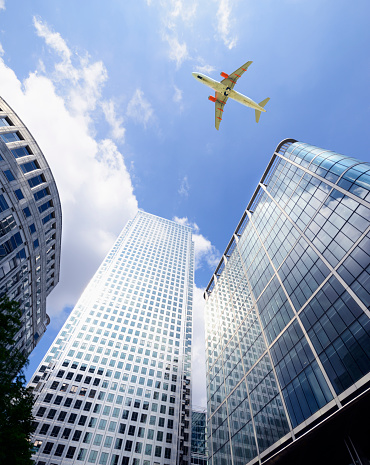 Airplane flying over skyscrapers, Canary Wharf, London - England