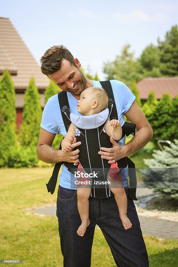 Father and baby Outdoor portrait of happy father carrying his baby in carrier. 6-11 Months Stock Photo