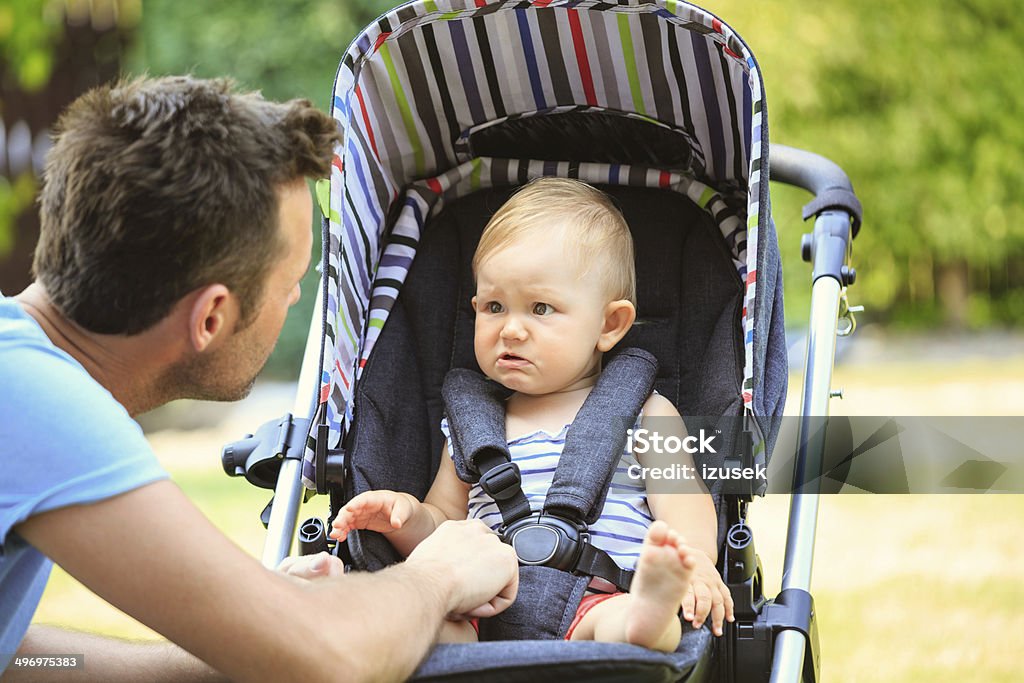 Father and baby Outdoor portrait of father consoling his crying baby sitting in a baby stroller. Baby Stroller Stock Photo