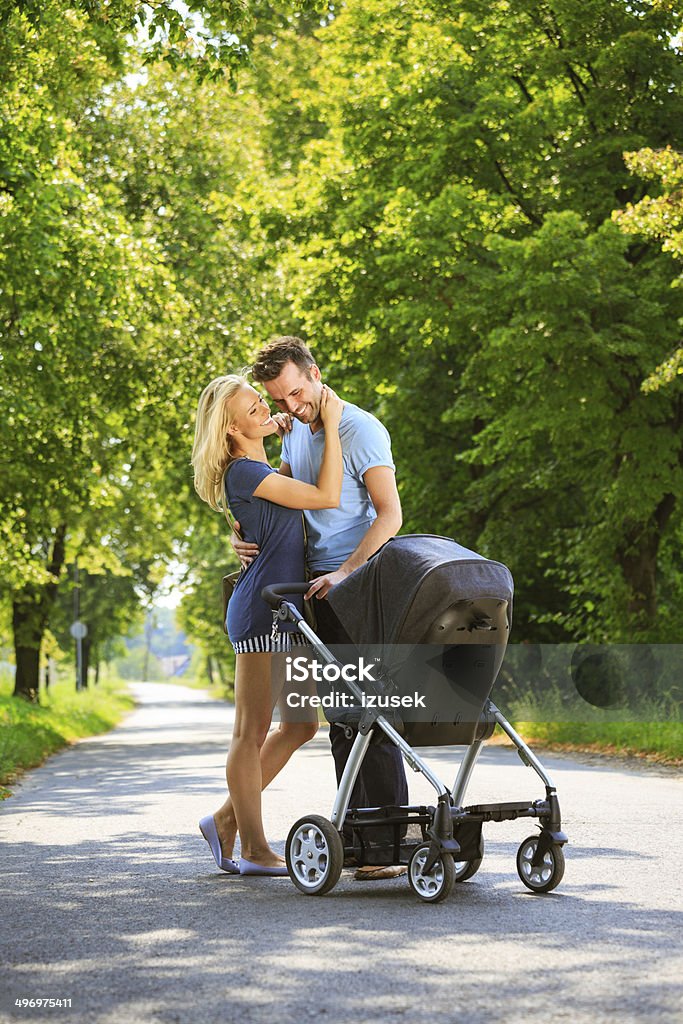 Happy couple in a park Outdoor portrait of happy couple walking with baby stroller in a park. Baby Stroller Stock Photo