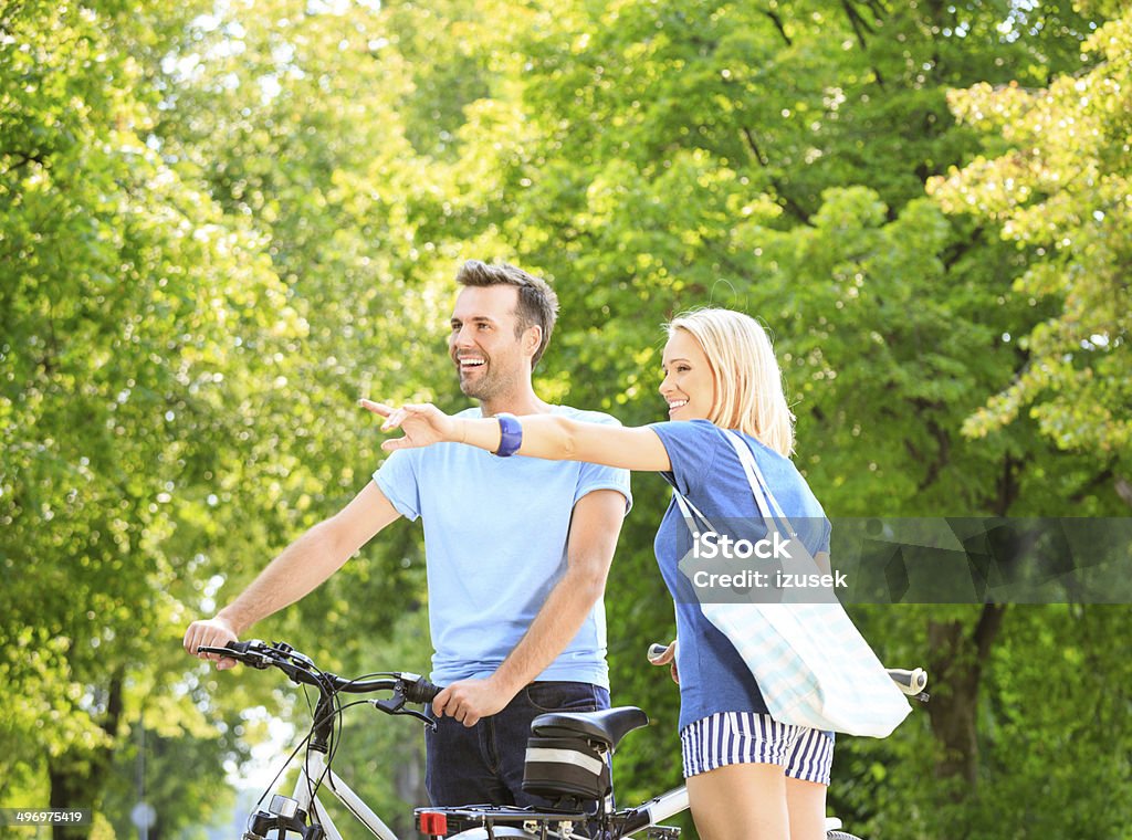 Happy couple in a park Outdoor portrait of happy couple standing with a bicycles in a park. Adult Stock Photo