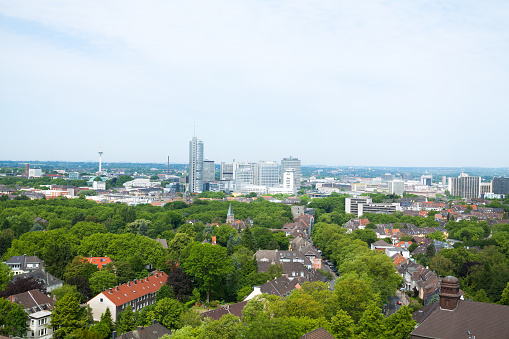 Aerial shot of modern skyline of Essen with office buildings of Evonik and RWE and Postbank. View over green trees in early summer.