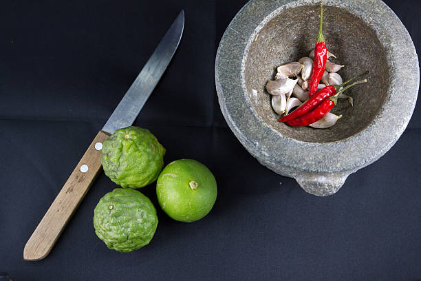 Chili, garlic in stone mortar and lemon,kaffir stock photo