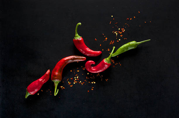 chili peppers su sfondo nero - pepper vegetable red green foto e immagini stock