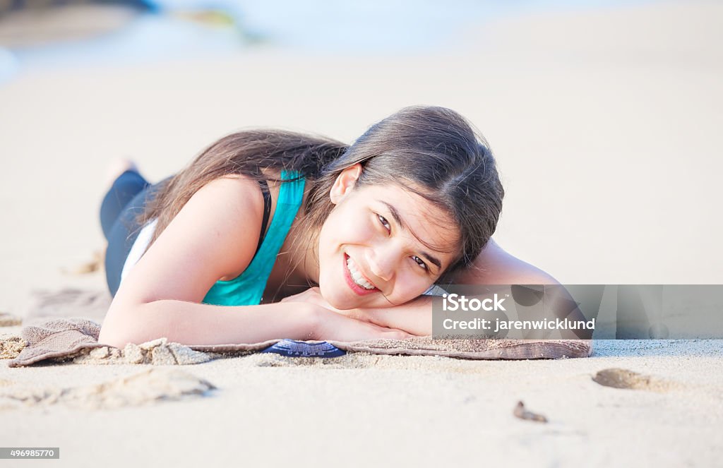 Biracial teen girl lying on sandy beach, resting and smiling Beautiful biracial Asian Caucasian teen girl lying on sandy beach, resting and smiling 2015 Stock Photo