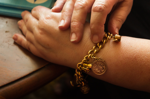Adult female wearing an antique gold charm bracelet.